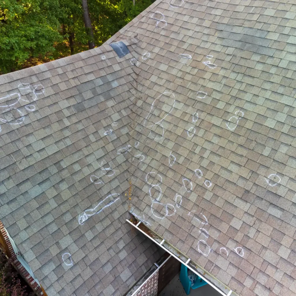 Hail damaged asphalt shingled roof marked with chalk, in Northern Michigan